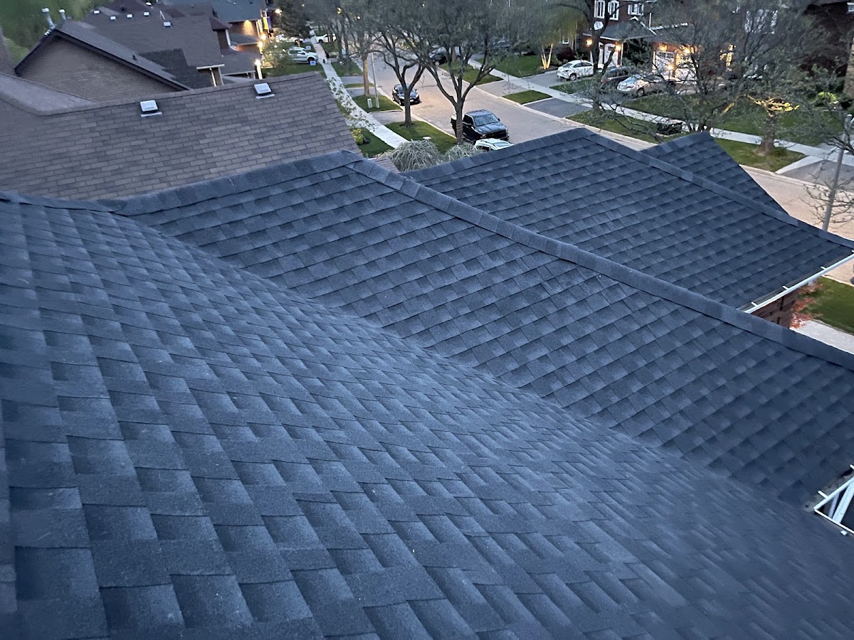 Finished charcoal shingle roof with clean valleys and ridge caps on a suburban home