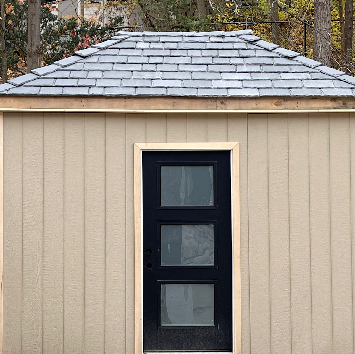 Shed with a new slate-look roof and a new black door with fresh wood trim